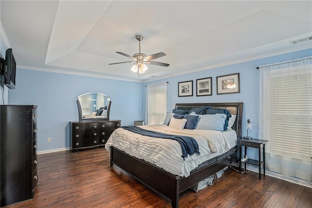 bedroom with ceiling fan, visible vents, wood finished floors, a raised ceiling, and baseboards
