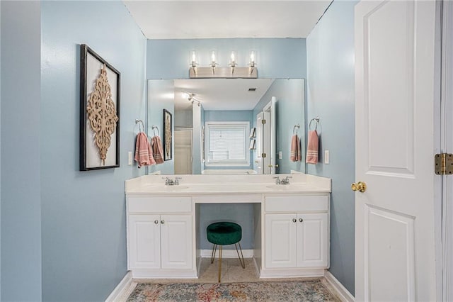 bathroom featuring a sink, baseboards, tile patterned floors, and double vanity