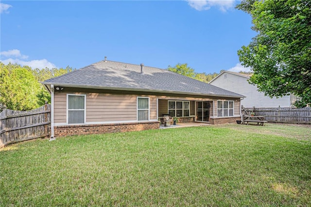 rear view of property with a fenced backyard, roof with shingles, brick siding, a patio area, and a yard