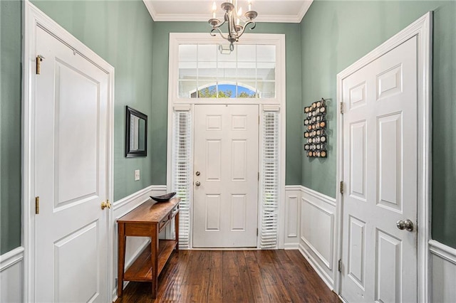 entryway featuring an inviting chandelier, a decorative wall, ornamental molding, a wainscoted wall, and dark wood-style floors