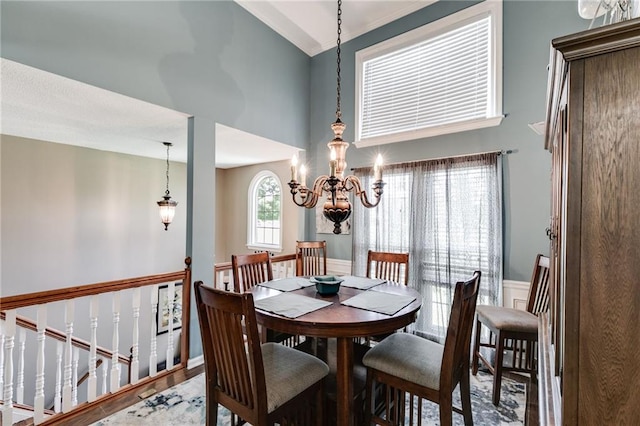 dining space with a towering ceiling, a chandelier, and wood finished floors