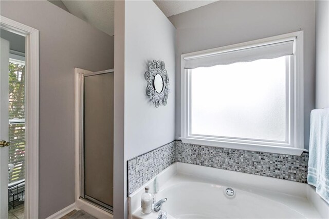 bathroom with a stall shower and a garden tub