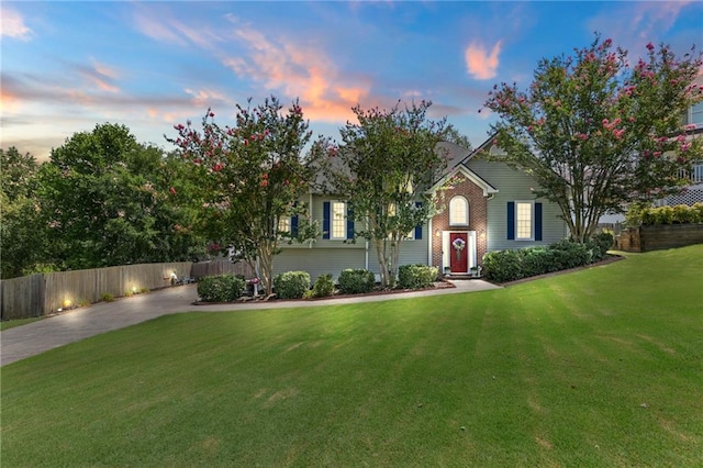 bi-level home with a yard, brick siding, and fence