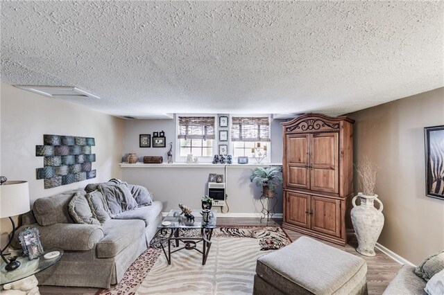 living area with a textured ceiling, wood finished floors, attic access, and baseboards