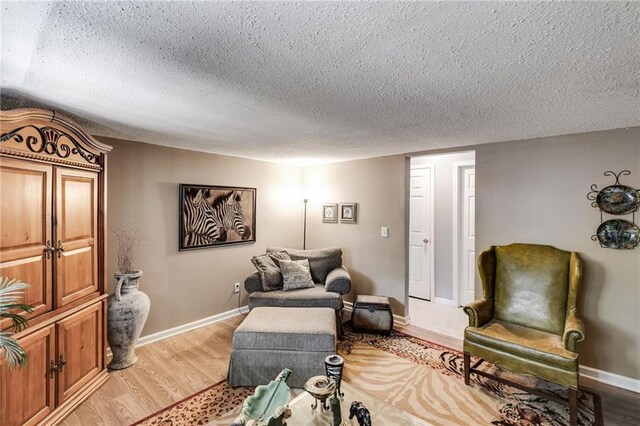 living area with light wood-style floors, baseboards, and a textured ceiling