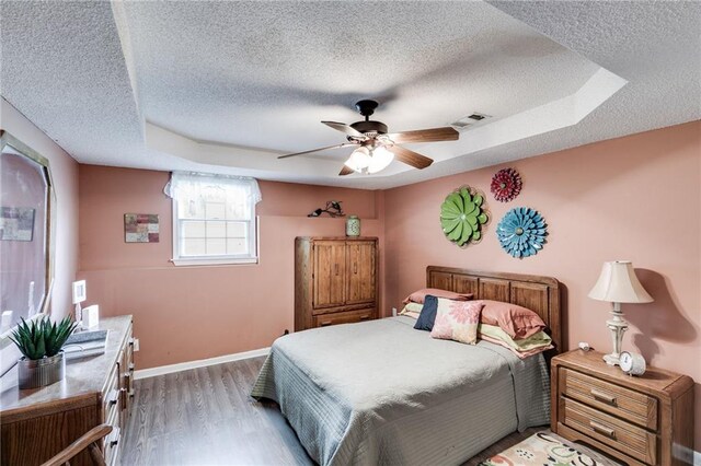 bedroom with light wood-style floors, baseboards, visible vents, and a textured ceiling