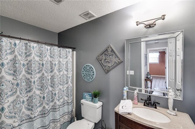 bathroom featuring visible vents, a shower with shower curtain, toilet, a textured ceiling, and vanity