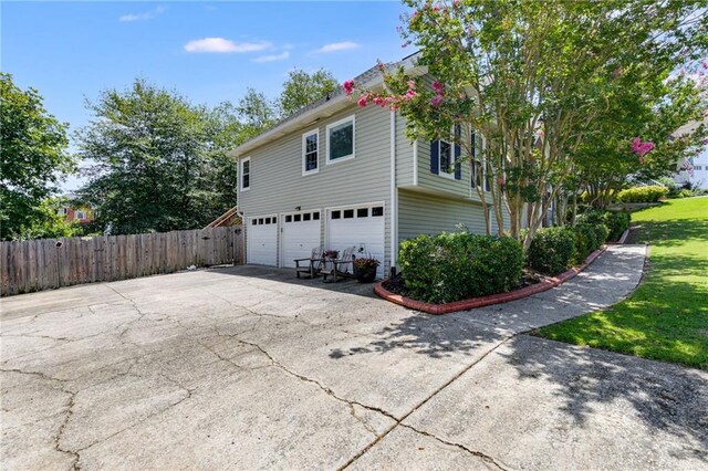 view of home's exterior with driveway, an attached garage, and fence