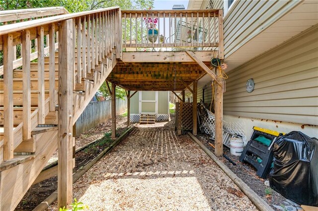 view of patio featuring a deck, an outbuilding, fence, stairs, and a carport