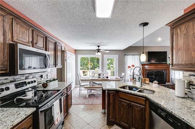 kitchen featuring light tile patterned floors, stainless steel appliances, a peninsula, a sink, and pendant lighting