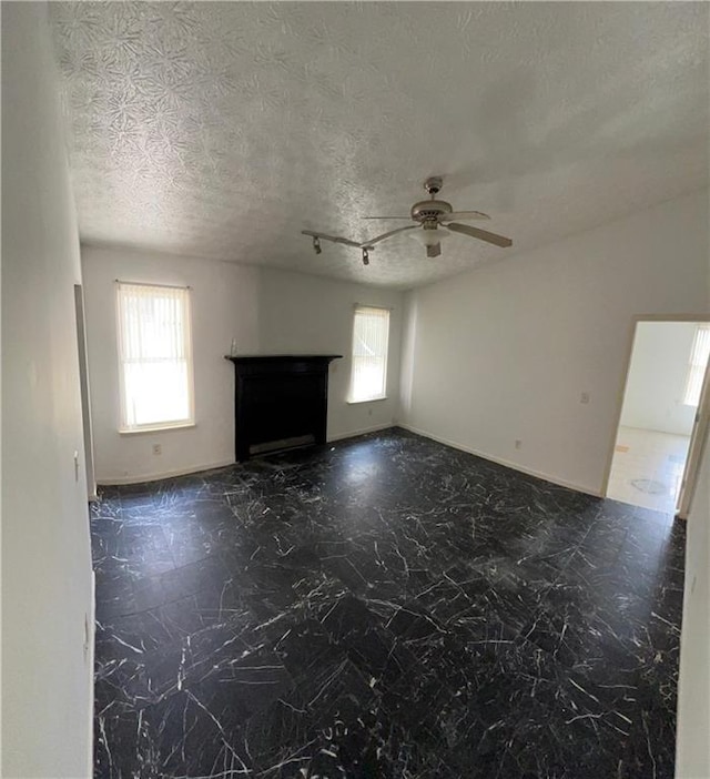 unfurnished living room with a healthy amount of sunlight, a fireplace, a ceiling fan, and a textured ceiling