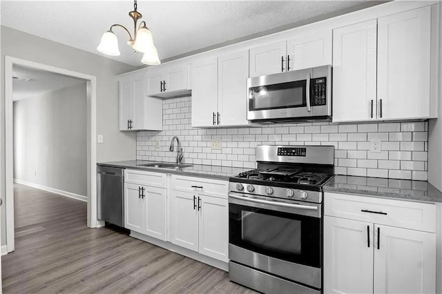 kitchen featuring decorative backsplash, appliances with stainless steel finishes, light wood-type flooring, sink, and white cabinets