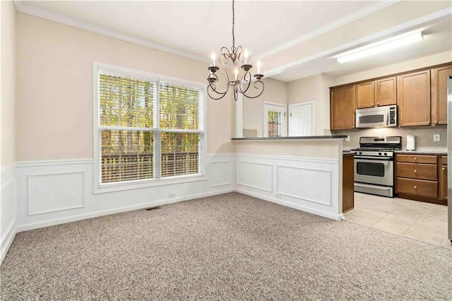 kitchen featuring an inviting chandelier, appliances with stainless steel finishes, hanging light fixtures, and light carpet