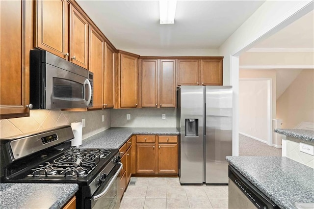 kitchen featuring crown molding, appliances with stainless steel finishes, decorative backsplash, and light tile patterned floors