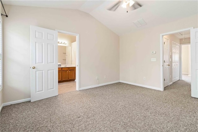 unfurnished bedroom with ceiling fan, light colored carpet, vaulted ceiling, and ensuite bath