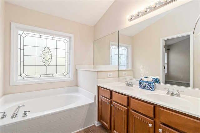 bathroom featuring tiled tub, vanity, and tile patterned floors