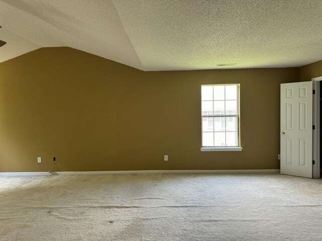 carpeted empty room featuring a textured ceiling and lofted ceiling