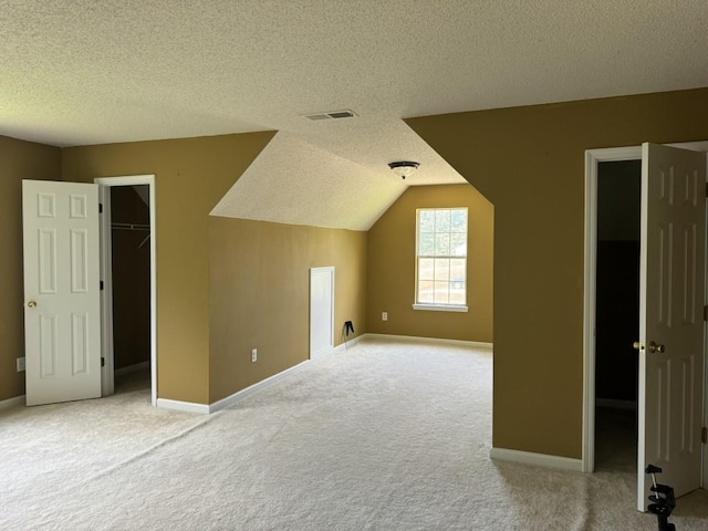 bonus room featuring a textured ceiling, light carpet, and lofted ceiling