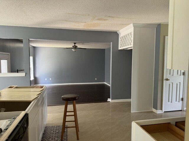 kitchen with dishwashing machine, light tile patterned floors, a textured ceiling, white cabinetry, and ceiling fan