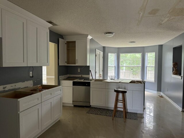 kitchen with a textured ceiling, dishwasher, kitchen peninsula, and white cabinetry