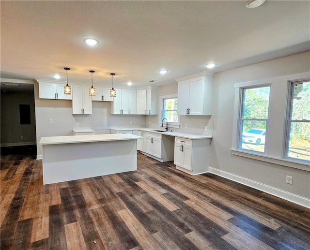 kitchen with pendant lighting, dark wood-type flooring, a kitchen island, and white cabinets