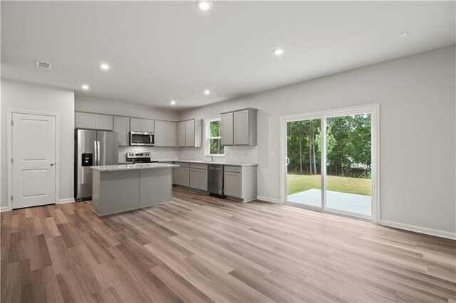 kitchen with gray cabinets, a center island, stainless steel appliances, and light wood-type flooring