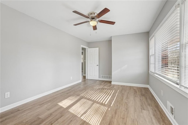 unfurnished room featuring baseboards, visible vents, and wood finished floors