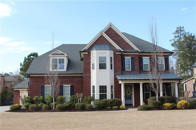 view of front of home with brick siding, covered porch, and a shingled roof