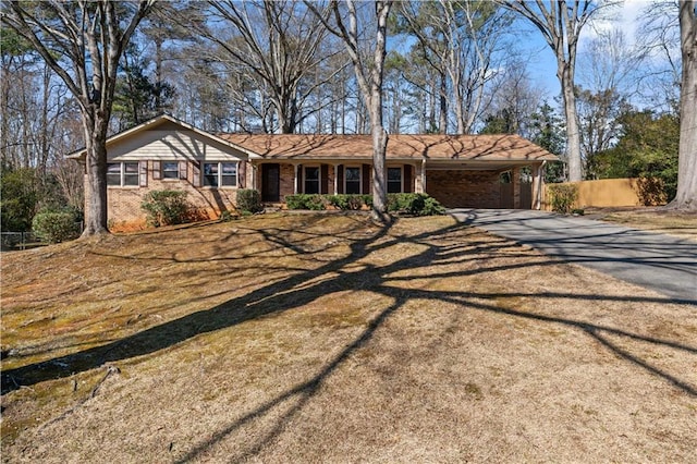 ranch-style house featuring an attached carport, brick siding, driveway, and fence