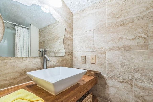 bathroom with a shower with shower curtain, a textured ceiling, and a sink