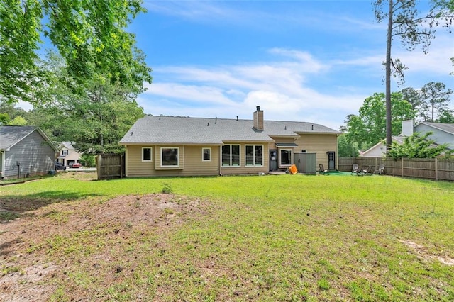 rear view of property with a lawn, a fenced backyard, and a chimney