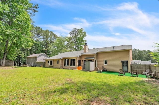 back of property featuring a lawn, fence, and a chimney