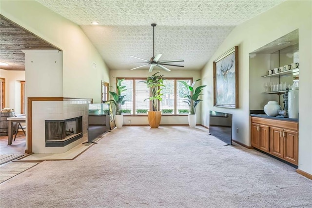 living area with ceiling fan, lofted ceiling, carpet, and a tile fireplace