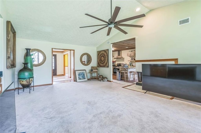 carpeted living room with visible vents, a textured ceiling, a ceiling fan, baseboards, and vaulted ceiling