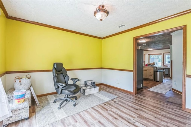 home office with baseboards, a textured ceiling, visible vents, and wood finished floors