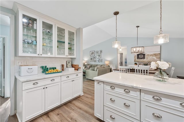 kitchen featuring white cabinetry, hanging light fixtures, light wood-style floors, and lofted ceiling