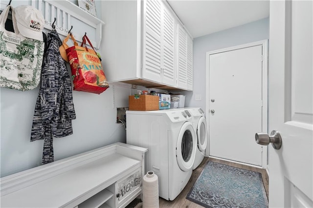 laundry area featuring cabinet space, light wood-style floors, and washer and dryer