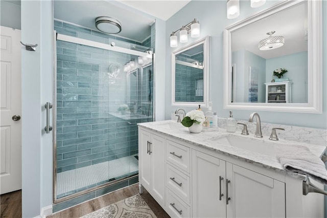 full bathroom featuring a stall shower, double vanity, wood finished floors, and a sink