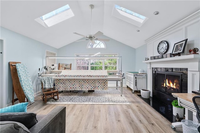 bedroom with lofted ceiling with skylight, baseboards, light wood-style floors, and a fireplace