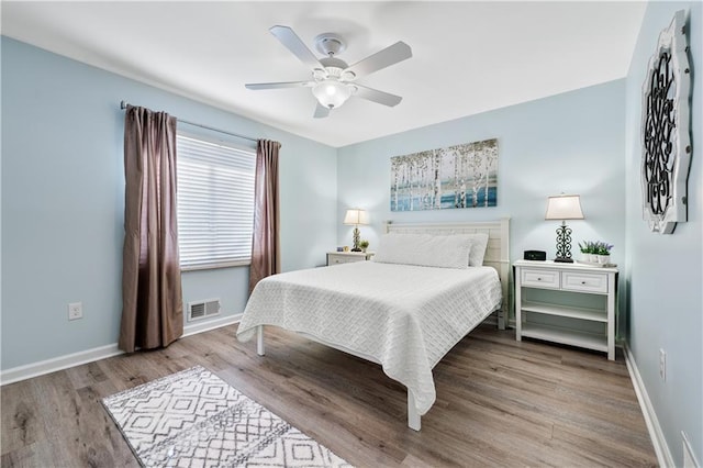 bedroom featuring baseboards, visible vents, wood finished floors, and ceiling fan