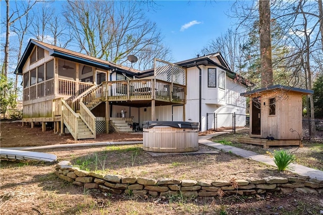 rear view of property with a sunroom, fence, stairs, a hot tub, and an outdoor structure