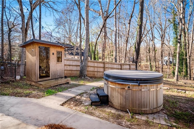 view of yard with a fenced backyard, an outbuilding, a shed, and a hot tub