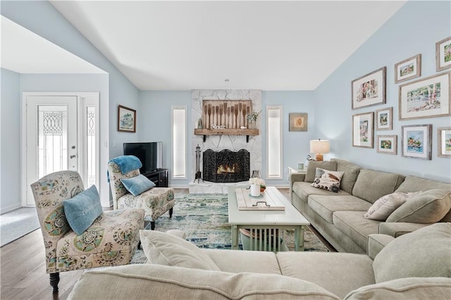 living room with a fireplace, baseboards, vaulted ceiling, and wood finished floors