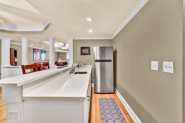 3125 Flatbottom Dr, Dacula, GA 30019 - kitchen with freestanding refrigerator, ornamental molding, a peninsula, ornate columns, and a sink