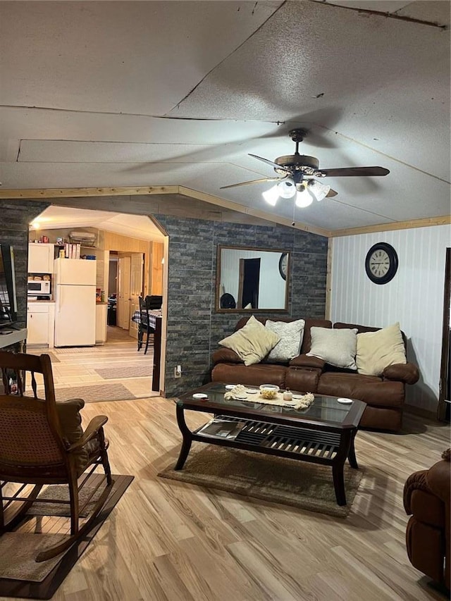 living room featuring light wood-type flooring, arched walkways, a ceiling fan, and vaulted ceiling