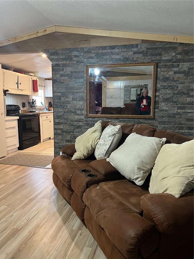 living area with a textured ceiling, vaulted ceiling, and light wood finished floors