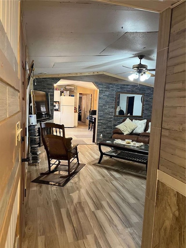 interior space featuring a textured ceiling, vaulted ceiling, light wood-type flooring, and ceiling fan