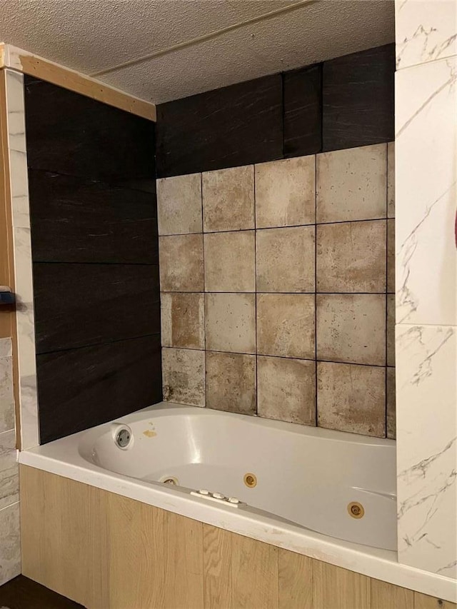 full bath featuring a textured ceiling and a tub with jets