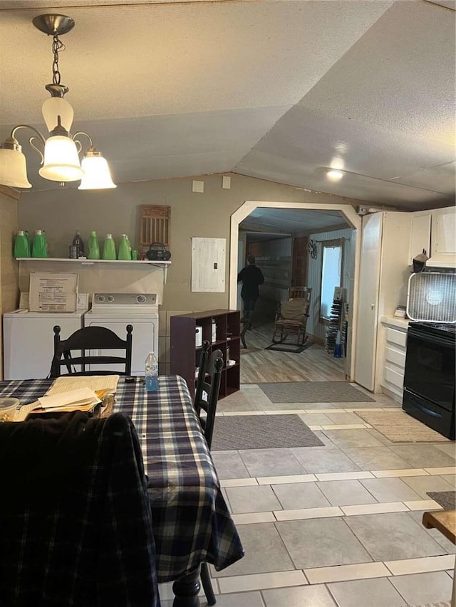 dining area with electric panel, separate washer and dryer, arched walkways, vaulted ceiling, and a textured ceiling