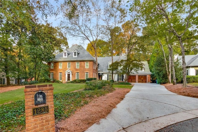 colonial-style house featuring a front yard, driveway, and an attached garage